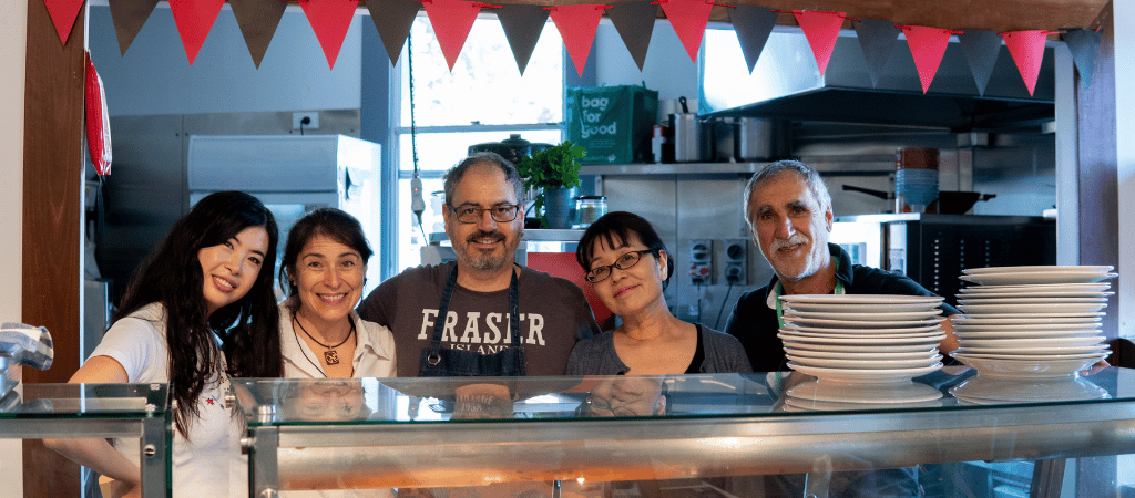 Five volunteers stand and smile in the ASC's industrial kitchen